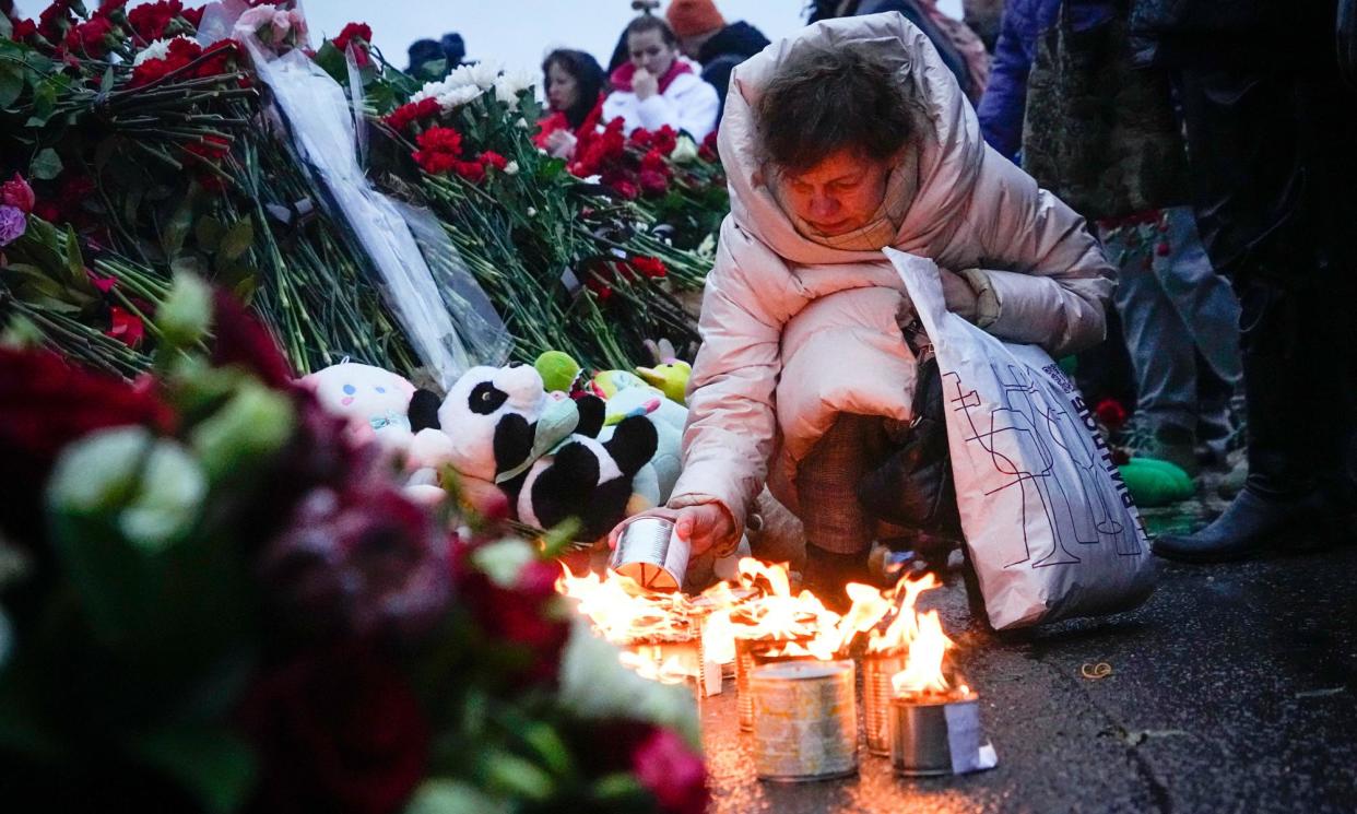 <span>A woman lights candles at the fence next to the Crocus City Hall venue where the attacks took place.</span><span>Photograph: Alexander Zemlianichenko/AP</span>