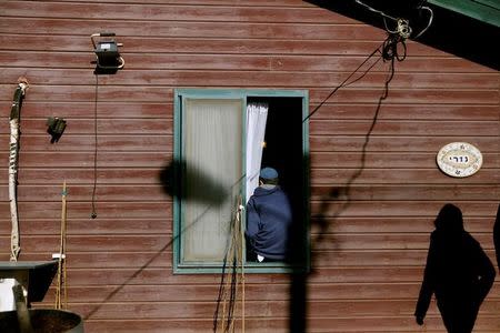 A youth sits on a window frame of a home in the Israeli settler outpost of Amona in the occupied West Bank February 1, 2017. REUTERS/Ronen Zvulun