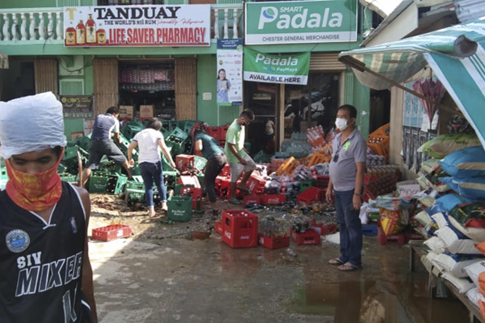 Residents arrange toppled soda bottles after a strong earthquake struck in Cataingan, Masbate province, central Philippines, Tuesday Aug. 18, 2020. A powerful and shallow earthquake struck a central Philippine region Tuesday, prompting people to dash out of homes and offices but there were no immediate reports of injuries or major damage. (AP Photo/ Christopher Decamon)