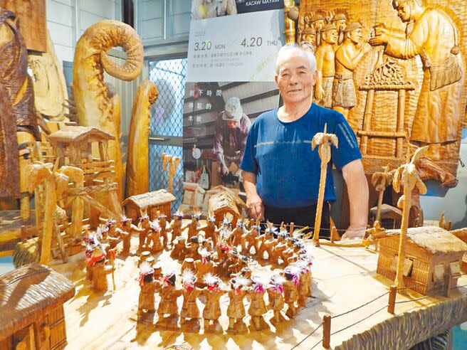 曾獲原住民族工藝薪傳獎的木雕工藝師胡銀祿（卡兆‧馬耀）與其最引以為傲的作品《重建》。（羅亦晽攝）