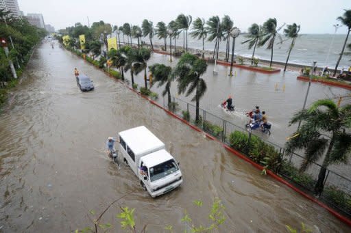 Commuters drive in flood waters brought on by Typhoon Saola on a road in Manila. More than 150,000 people across the Philippines have been forced to flee their homes this week as Typhoon Saolo, hovering to the north of the country, has added to monsoon weather, the national disaster management council said