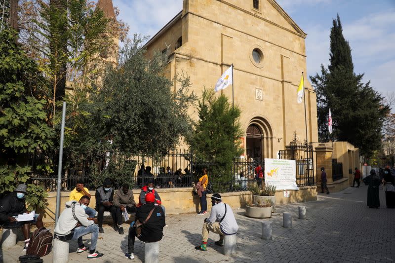 Migrants wait for assistance outside the Holy Cross Catholic Church next to the United Nations buffer zone in Nicosia