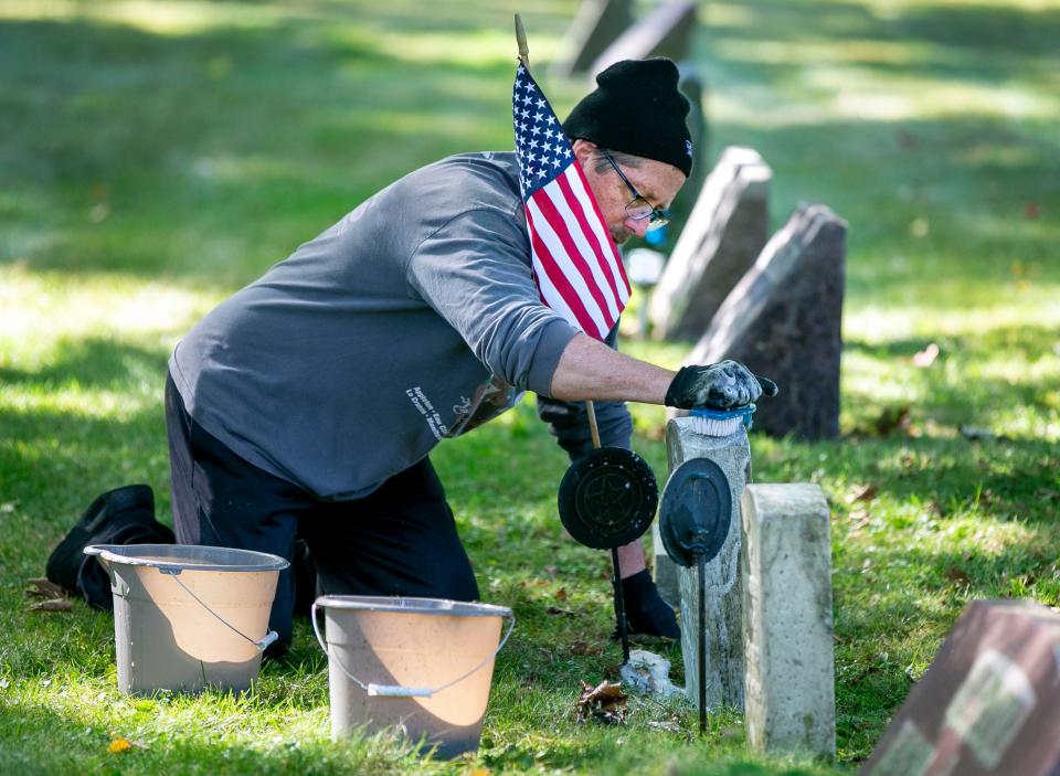 Pete Reinke, of Manitowoc, scrubs away at Civil War veteran gravestone at Evergreen Cemetery on Oct. 1, 2022, in Manitowoc, Wis.