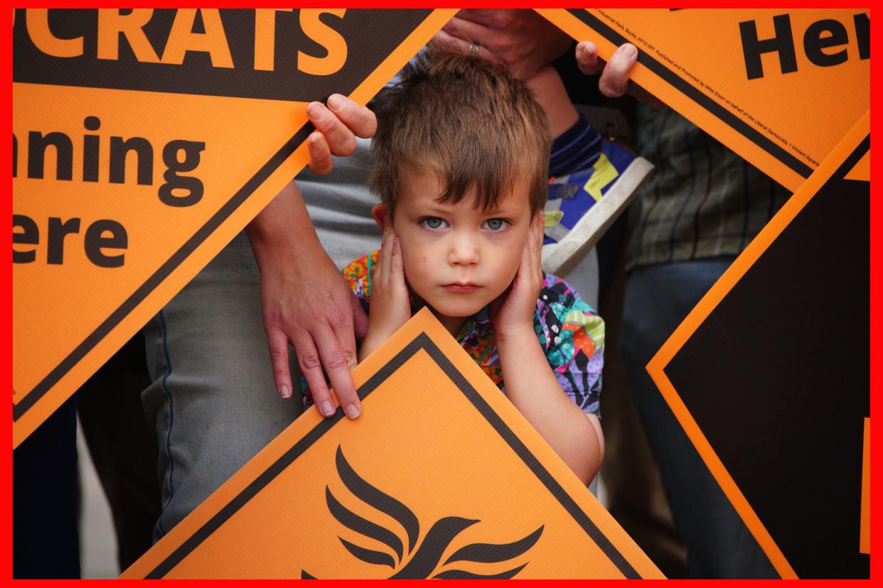 Four year old Sam Palmer-White covers his ears during the celebrations as newly elected Liberal Democrat MP Sarah Dyke meets up with party leader Sir Ed Davey in Frome (PA)
