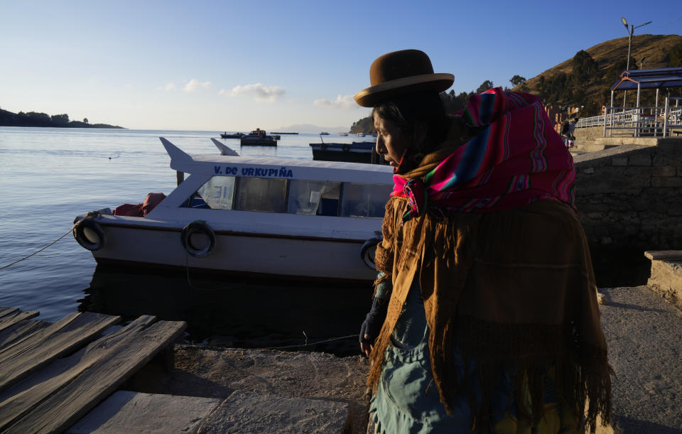 Una mujer aymara camina junto a la orilla del lago Titicaca, en el puerto de Tiquina, Bolivia, el 27 de julio de 2023. El bajo nivel del agua en el lago está teniendo un impacto directo en la flora y la fauna locales y afecta a las comunidades locales que dependen de la frontera natural entre Perú y Bolivia para su sustento. (AP Foto/Juan Karita)