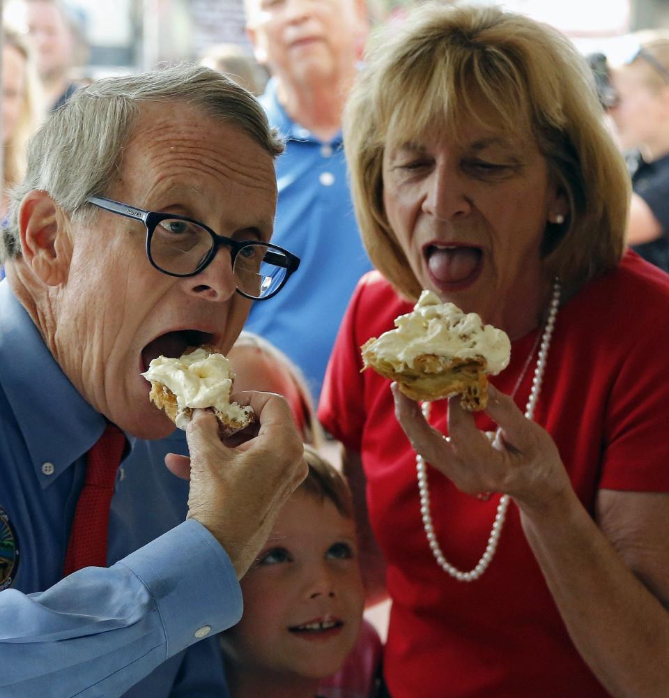 Ohio Gov. Mike DeWine and wife Fran eat cream puffs at Schmidt's stand while grandchild Steven Dudukovich  waits his turn at the 2019 Ohio State Fair.