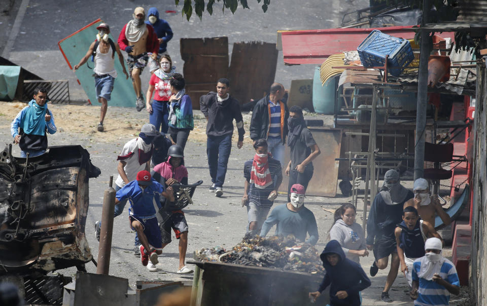 In this Monday, Jan. 21, 2019 photo, anti-government protesters clash with security forces as they show support for an apparent mutiny by a national guard unit in the Cotiza neighborhood of Caracas, Venezuela. The uprising triggered protests which were dispersed with tear gas as residents set fire to a street barricade of trash and chanted demands that President Nicolas Maduro leave power. (AP Photo/Ariana Cubillos)