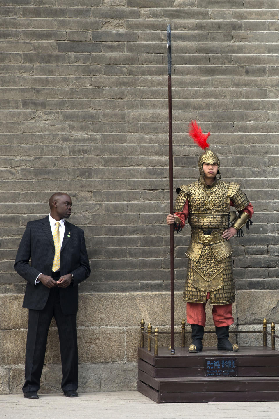 A U.S. secret service officer checks a Chinese performer dressed as an ancient warrior as U.S. first lady Michelle Obama visits a nearby city wall in Xi'an, in northwestern China's Shaanxi province, Monday, March 24, 2014. (AP Photo/Alexander F. Yuan)