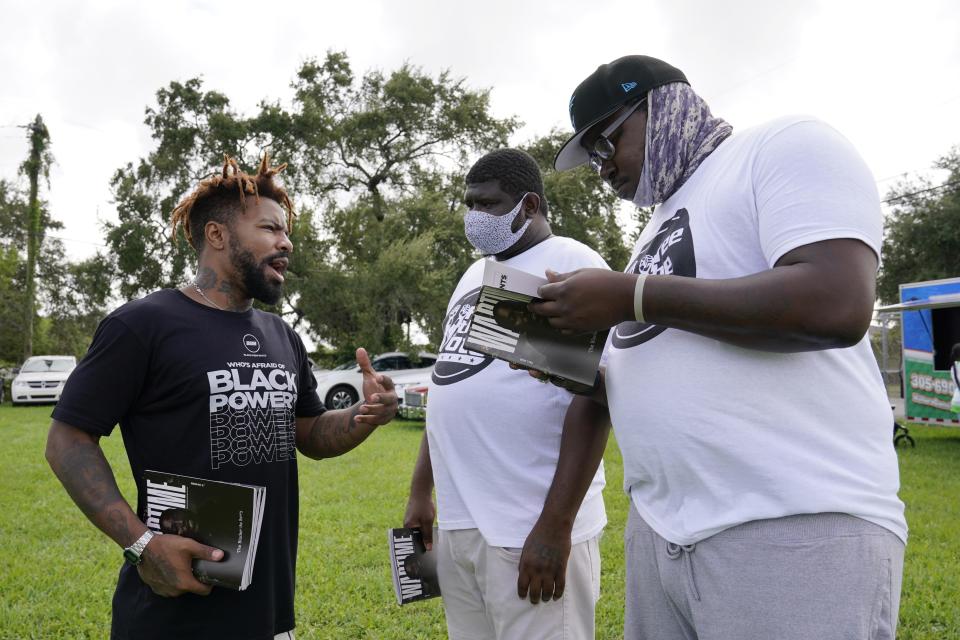 Phillip Agnew, left, a leader of Black Men Build, speaks to Derrick Williams, right, and Davion Frazier at a "Free the Vote" rally to the polls, Saturday, Oct. 24, 2020, in Miami. Get out the vote efforts targeting Black men aren’t just about persuading them to choose former Vice President Joe Biden over incumbent Donald Trump. “We are not choosing a champion, we are choosing an opponent,” says activist Agnew. (AP Photo/Marta Lavandier)