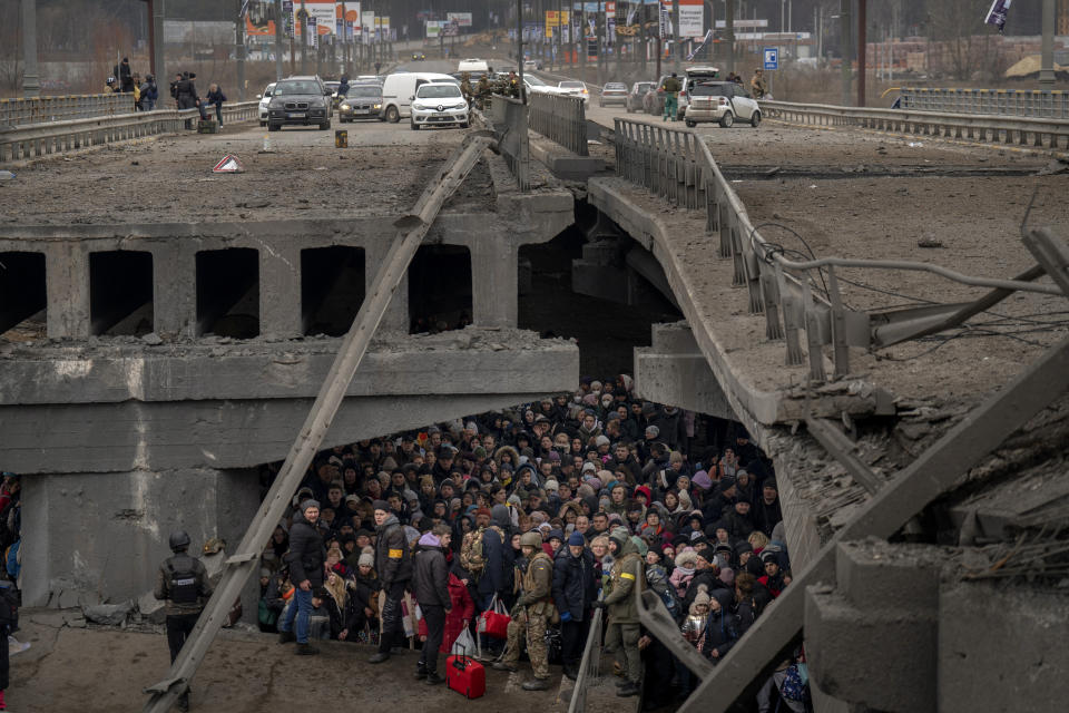 Un grupo de ucranianos se apiña bajo un puente dañado mientras intentan huir cruzando el río Irpin en las afueras de Kiev, Ucrania, el 5 de marzo de 2022. (AP Foto/Emilio Morenatti)