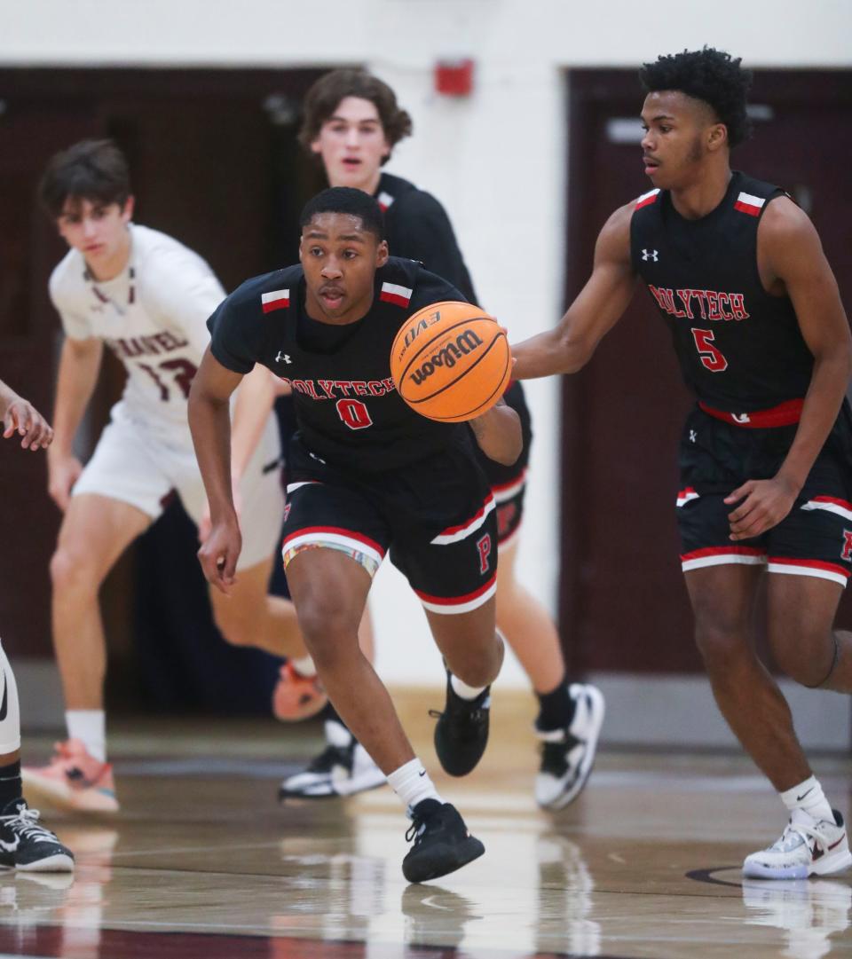 Polytech's Xavier Brewington (0) takes the ball up court in front of teammate Dorell Little (5) in the first half of Caravel's 84-62 win at Caravel Academy Tuesday, Feb. 14, 2023.