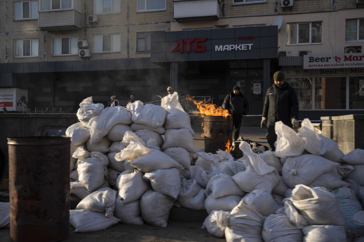 Members of the territorial defense warm themselves with a fire at a check point in Kyiv, Ukraine, Sunday, March 27, 2022. (AP Photo/Rodrigo Abd)