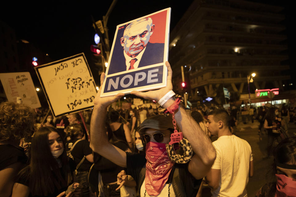 Israeli protesters hold signs and chant slogans during a demonstration against Israeli Prime Minister Benjamin Netanyahu near the Prime Minister's residence in Jerusalem, Sunday, Sept. 20, 2020. (AP Photo/Sebastian Scheiner)