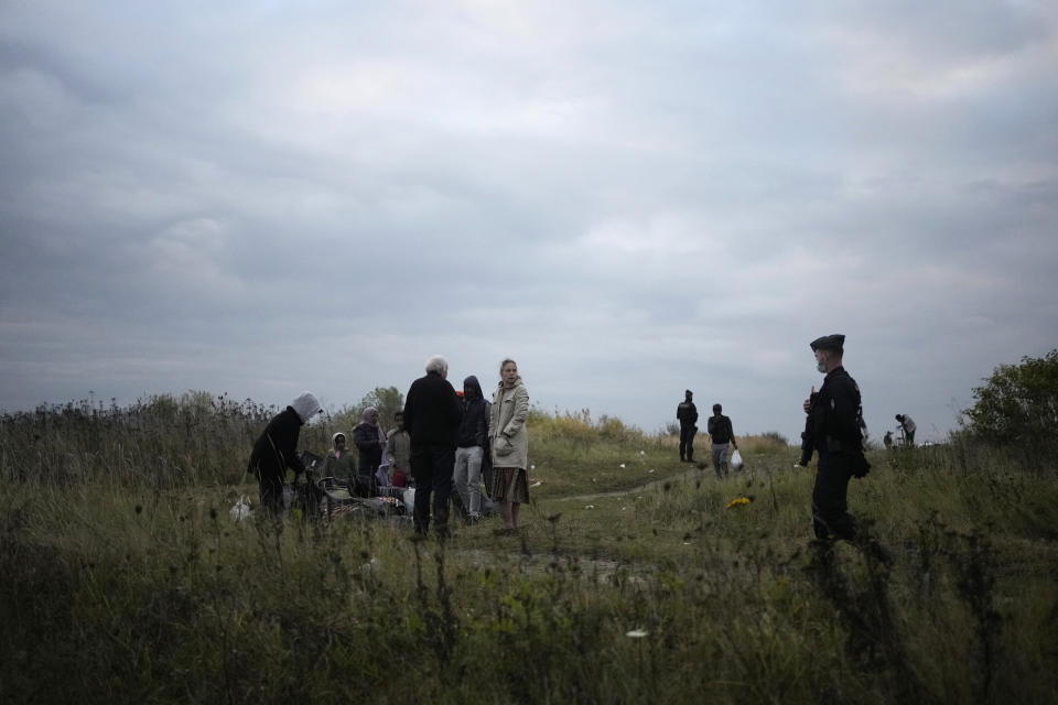 Police officers patrol near a migrant camp in Calais, northern France, Thursday, Oct. 14, 2021. While some migrants with money can pay to go to Britain on flimsy, overcrowded boats in often dangerous waters, the ones who can’t have to jump on one of the tens of thousands commercial trucks that pass each week between France and Britain. (AP Photo/Christophe Ena)