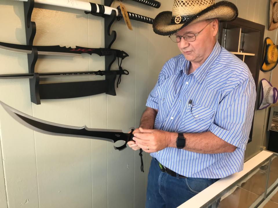 Ed Miller, owner of Fremont Cutlery Co., holds a sword at the Fremont retail knife store Saturday. The new business opened earlier in June at 823 W. State St.