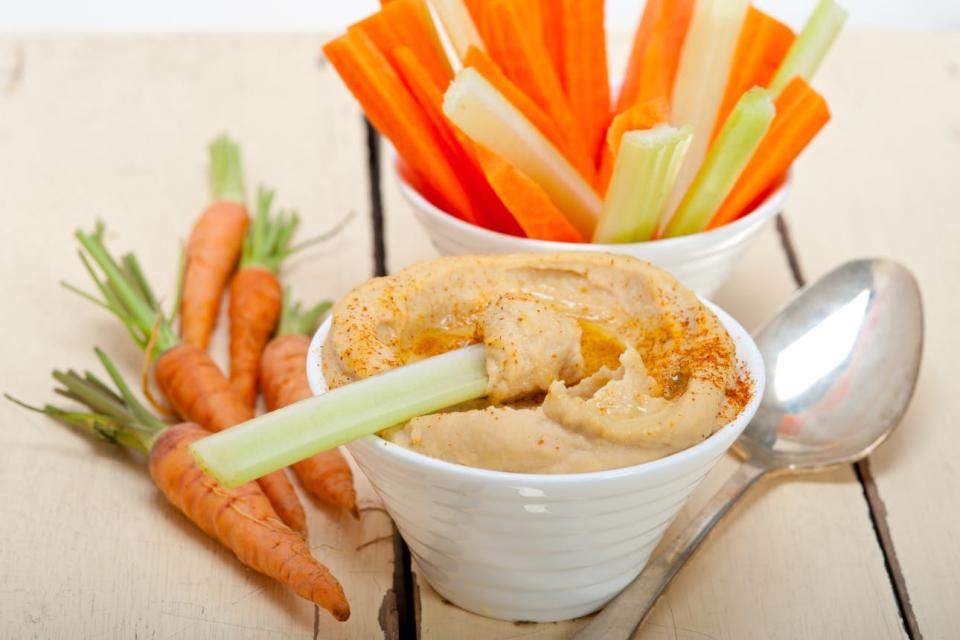 Fresh hummus is served with celery and carrot sticks