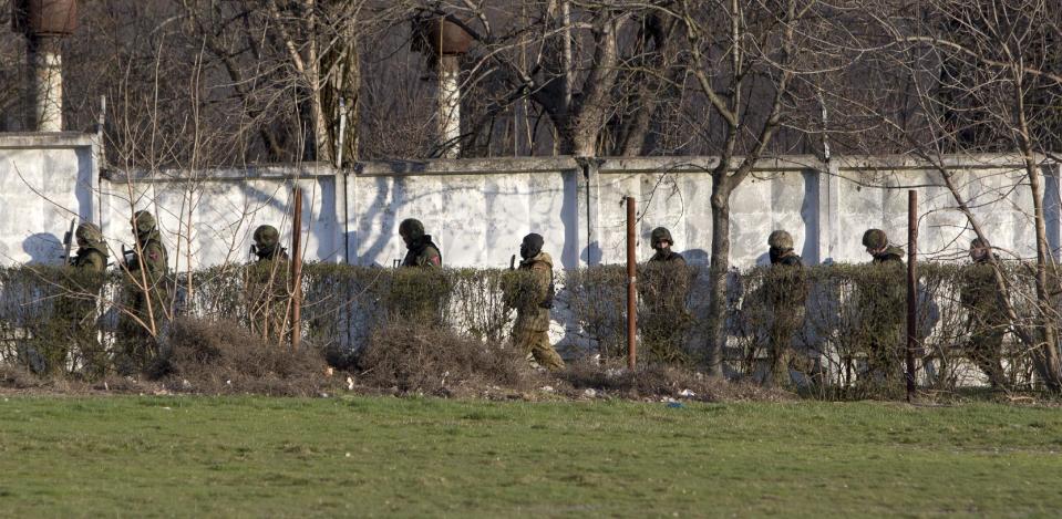 Unidentified armed men search an area close to an Ukrainian military unit in Simferopol, Crimea, on Tuesday, March 18, 2014. Gunfire at the military facility in the capital of separatist Crimea killed one serviceman and a member of a local self-defense brigade, a police spokeswoman was quoted as saying by the Interfax news agency. (AP Photo/Andrei Udovichenko)