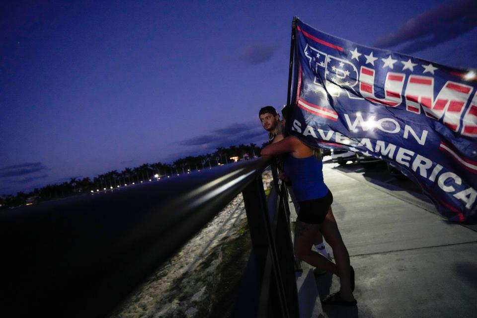 People hold a flag to show their support for former President Donald Trump following the news of his indictment on Thursday, March 30, 2023.