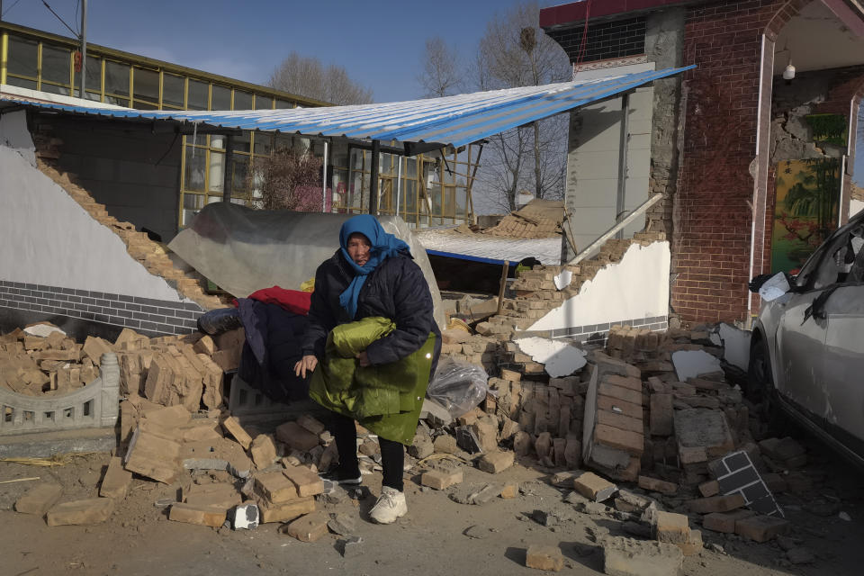 A woman collects clothes from her damaged home after the earthquake in Jishishan county, in northwest China's Gansu province, Tuesday, Dec. 19, 2023. The strong earthquake that hit northwest China and killed at least 148 people, has caused tens of millions of estimated economic losses in the agricultural and fisheries industries, state media reported Saturday, Dec. 23, 2023. (Chinatopix Via AP)