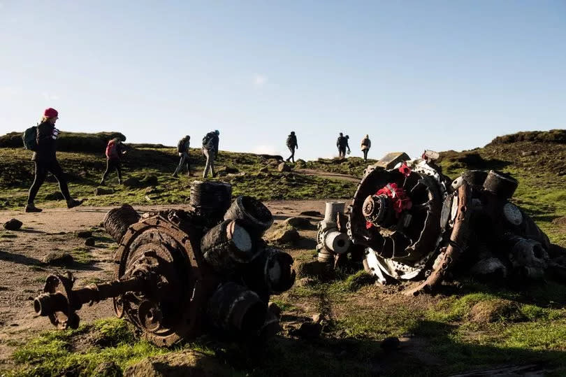 Walkers pass by the remains of the aircraft which crashed killing all of its crew