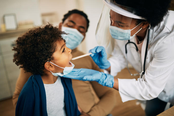 Family doctor examining child's throat.