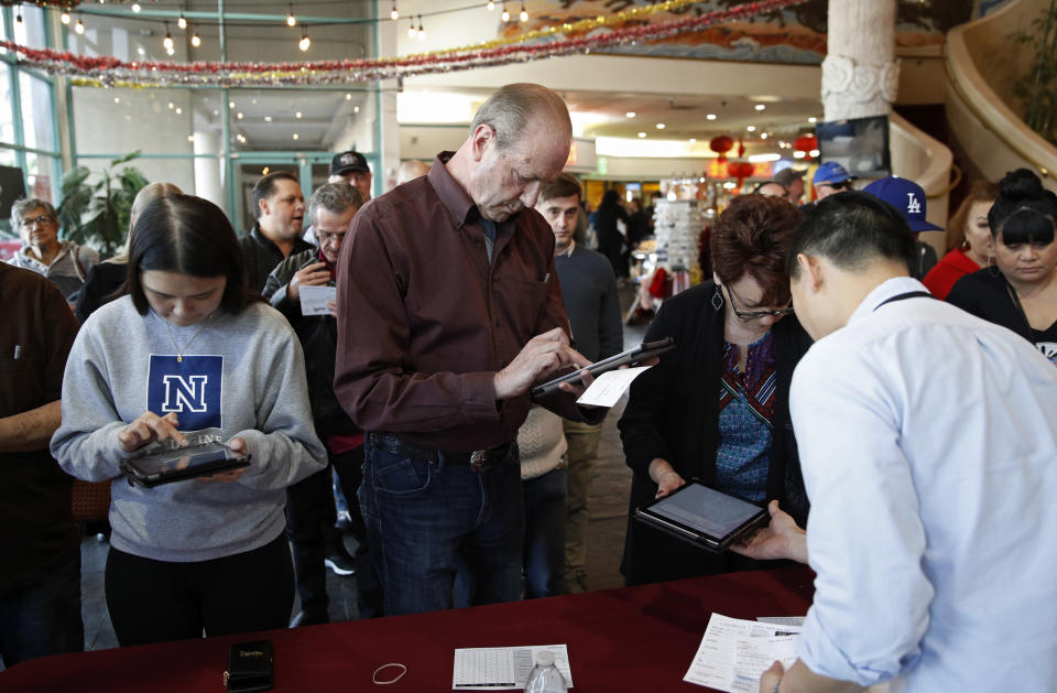 FILE - In this Feb. 15, 2020, file photo sign in on tablet computers at an early voting location in the Chinatown Plaza, in Las Vegas. Nevada Democrats are hoping to avoid a repeat of the chaos that ensnared the Iowa caucuses, as voters gather across the Silver State on Saturday to make their presidential preferences known. Iowa's process cratered this month following a rushed effort by state Democrats to deploy a mobile app for caucus volunteers to report results. Democrats in Nevada were going to use the same app developer as Iowa did, but quickly sidelined those plans. They will still be relying to some extent on technology to assist in counting and reporting results, though, and like Iowa, they will have paper backups. (AP Photo/John Locher, File)