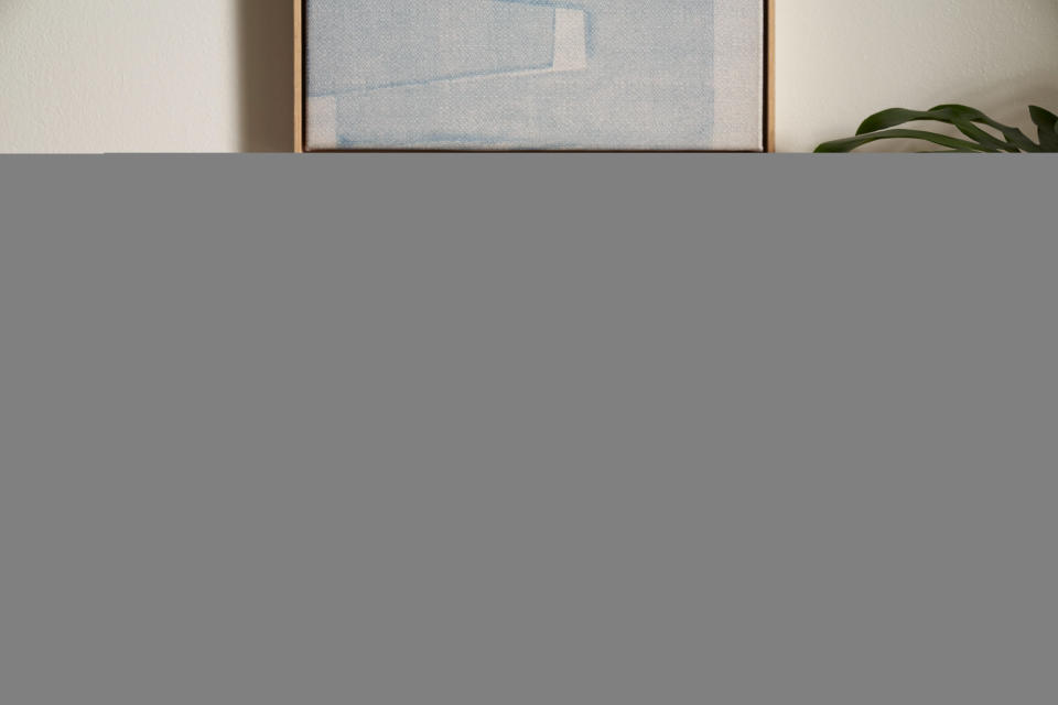 Sonos Era 300 in white on a wooden sideboard under a picture, between a plant and some books