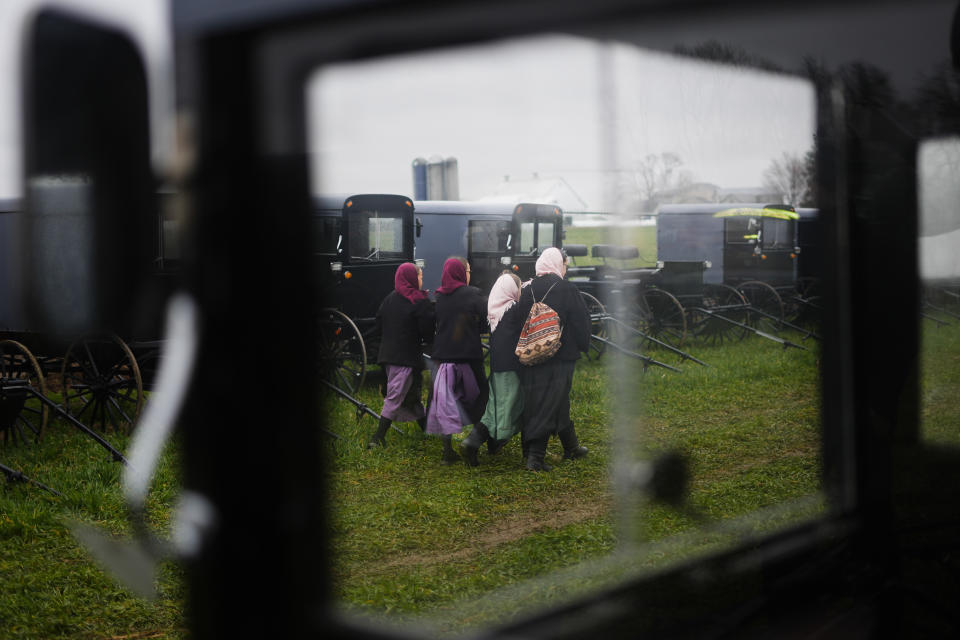 Young people walk amongst buggies that will be auctioned off during the 56th annual mud sale to benefit the local fire department in Gordonville, Pa., Saturday, March 9, 2024. Mud sales are a relatively new tradition in the heart of Pennsylvania's Amish country, going back about 60 years and held in early spring as the ground begins to thaw but it's too early for much farm work. (AP Photo/Matt Rourke)