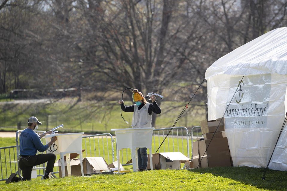 Volunteers assemble sinks at the Samaritan's Purse field hospital in New York's Central Park, Wednesday, April 1, 2020. The new coronavirus causes mild or moderate symptoms for most people, but for some, especially older adults and people with existing health problems, it can cause more severe illness or death. (AP Photo/Mary Altaffer)