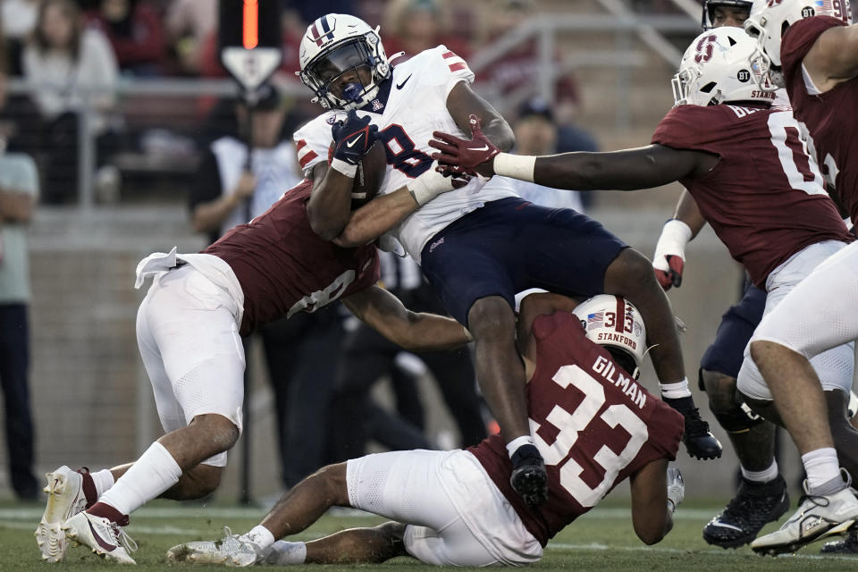 Arizona running back DJ Williams, center top, is tackled by Stanford linebacker Tristan Sinclair, left, and safety Alaka'i Gilman (33) during the second half of an NCAA college football game Saturday, Sept. 23, 2023, in Stanford, Calif. (AP Photo/Godofredo A. Vásquez)