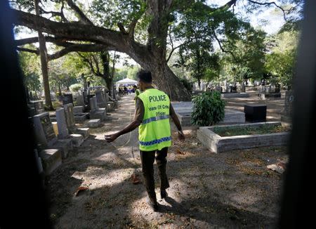 A police officer from the criminal investigations department prepares to exhumes the body of Lasantha Wickrematunge at a cemetery in Colombo, Sri Lanka September 27, 2016.REUTERS/Dinuka Liyanawatte