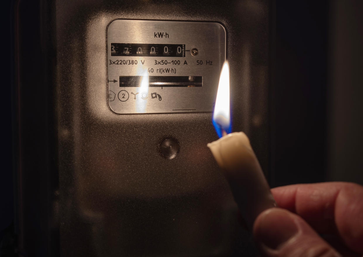 National Grid The electricity meter is illuminated by the light of a candle. Power outage, blackout concept.