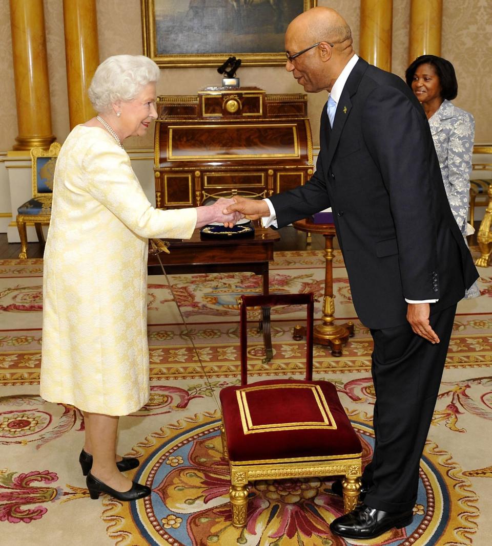 LONOND - JUNE 12: Queen Elizabeth II, knights Governor-General Of Jamaica Sir Patrick Allen on June 12, 2009 in London, England. Allen, who was accompanied by his wife Patricia,was presented with his credentials during a private audience at Buckingham Palace. (Photo by Tim Ireland/WPA Pool/Getty Images)