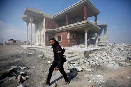 A Sunni Arab fighter walks near a house, which the residents of the village said belonged to a man who joined the Islamic State militants and was destroyed in an explosion, in Rfaila village in the south of Mosul, Iraq, February 17, 2017. Picture taken February 17, 2017. REUTERS/Khalid al Mousily