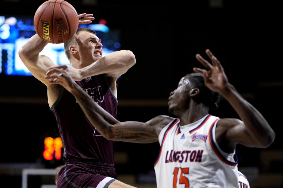 Langston guard Cortez Mosley (15) tries to block a shot by Freed-Hardeman forward Peyton Law, left, during the first half of the NAIA men's national championship college basketball game, Tuesday, March 26, 2024, in Kansas City, Mo. (AP Photo/Charlie Riedel)