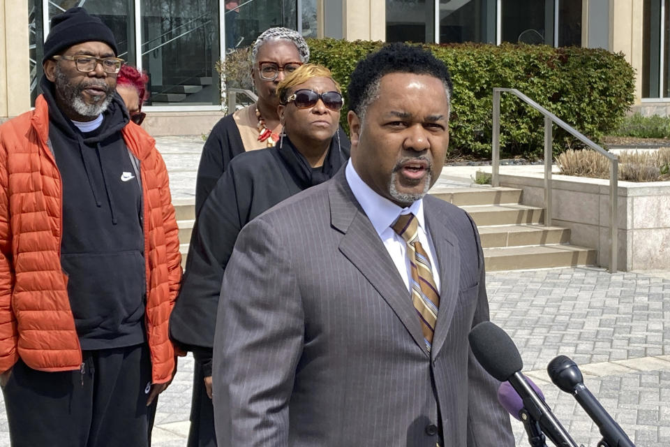 Family attorney Carl Crews, front, along with Timothy McCree Johnson's parents Melissa Johnson, rear center, and Timothy Walker, left, address reporters outside Fairfax County Police headquarters, Wednesday, March 22, 2023, in Fairfax, Va., after viewing police body camera video of their son's shooting death at the hands of police last month outside Tysons Corner Center shopping mall. (AP Photo/Matthew Barakat)