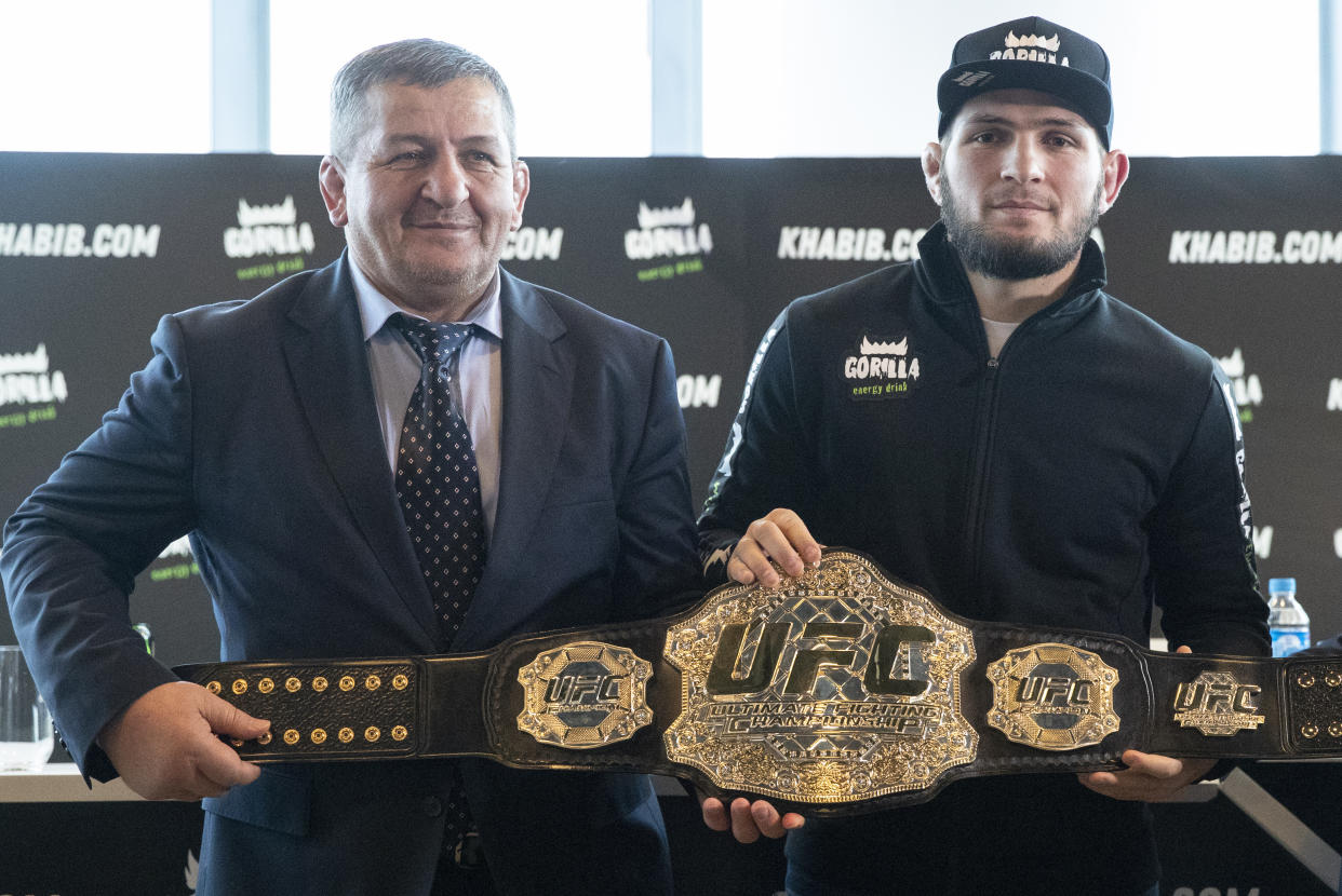 UFC lightweight champion Khabib Nurmagomedov, right, and his father Abdulmanap Nurmagomedov pose with the trophy belt during a news conference in Moscow, Russia, Monday, Nov. 26, 2018. The Russian professional mixed martial arts fighter Nurmagomedov, said he can imagine a reconciliation with Conor McGregor after the bitter feud around last month's title fight, but said he would like to fight Floyd Mayweather Jr.  (AP Photo/Pavel Golovkin)