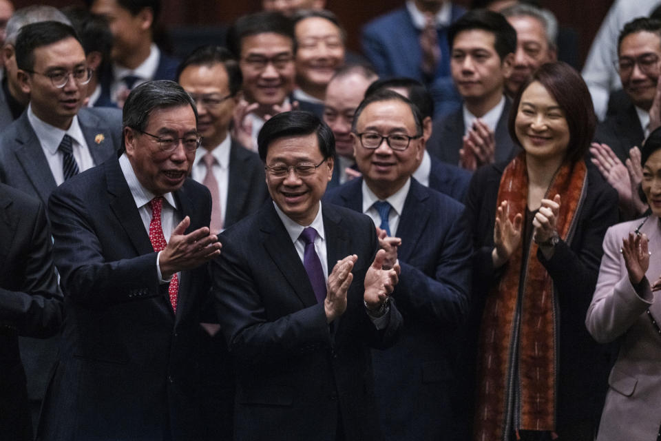 Hong Kong's Chief Executive John Lee Ka-chiu applauds with lawmakers following the passing of the Basic Law Article 23 legislation at the Legislative Council in Hong Kong, Tuesday, March 19, 2024. (AP Photo/Louise Delmotte)