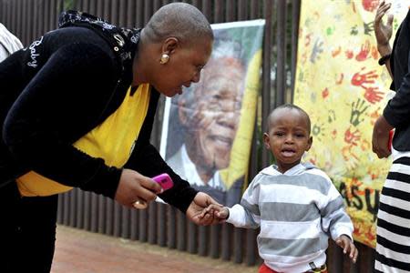 A mother consoles her crying son during a gathering for people mourning the death of former South African President Nelson Mandela on Vilakazi Street in Soweto, where Mandela resided when he lived in the township, December 6, 2013. REUTERS/Ihsaan Haffejee