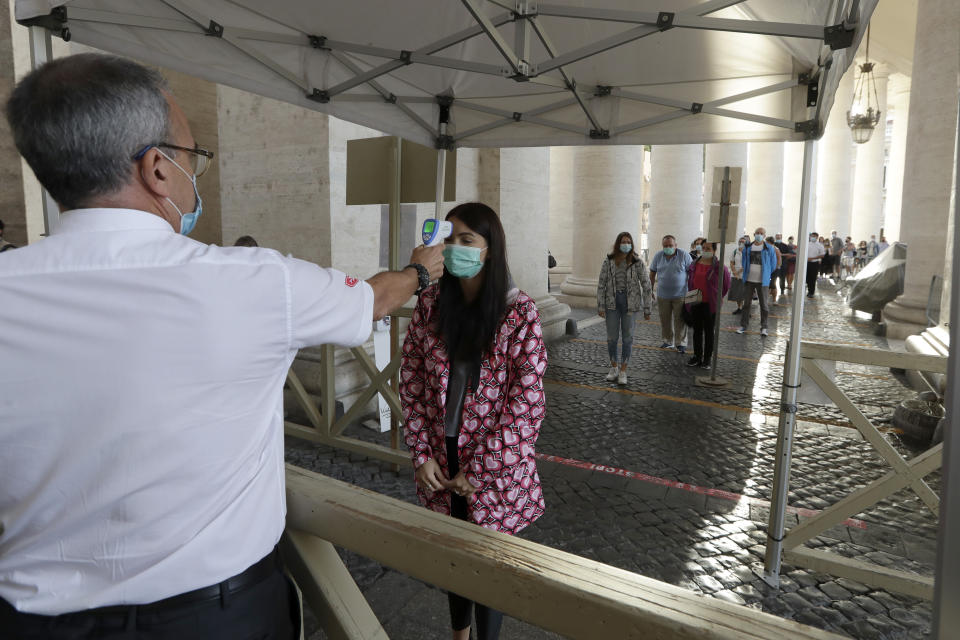 Vatican security checks the temperature of a woman for possible COVID-19 symptoms as she arrives to attend Pope Francis' first general audience with faithful since February when the coronavirus outbreak broke out, at the Vatican, Wednesday, Sept. 2, 2020. (AP Photo/Andrew Medichini)