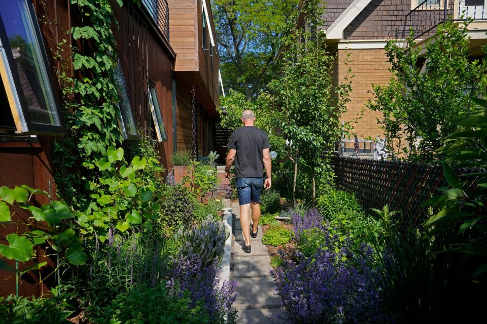 Mike Maschek walks through a garden area alongside his Riverwest home that he shares with his wife, Juli Kaufmann, on June 19, 2023. The home will be part of the Riverwest Secret Garden Tour on July 9.