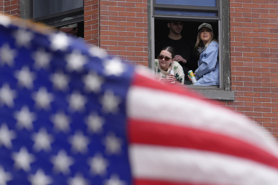 Spectators watch the St. Patrick's Day parade from a window, Sunday, March 17, 2024, in Boston's South Boston neighborhood. (AP Photo/Steven Senne)