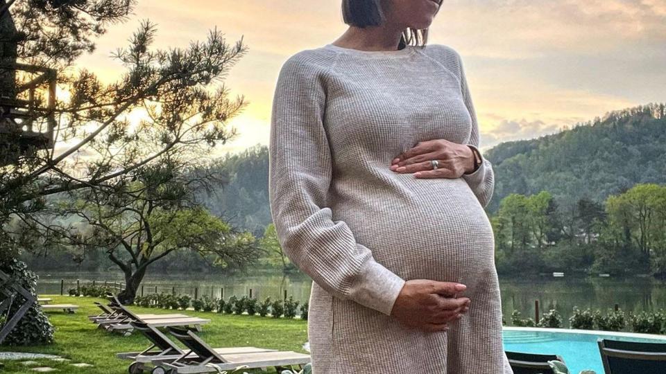 janette manrara wearing beige jumper dress and cradling baby bump