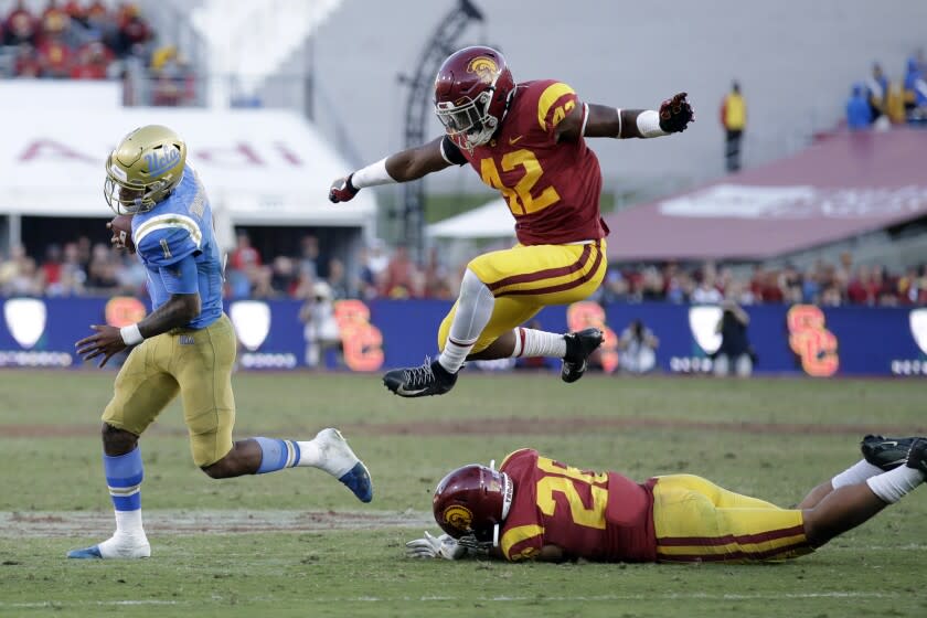 UCLA quarterback Dorian Thompson-Robinson, left, is chased by Southern California linebacker Abdul-Malik McClain (42) during the second half of an NCAA college football game, Saturday, Nov. 23, 2019, in Los Angeles. (AP Photo/Marcio Jose Sanchez)
