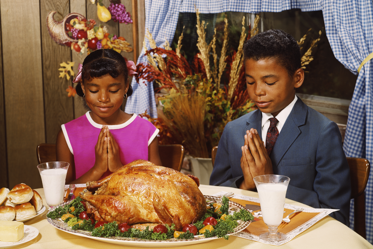 A boy and girl saying grace before a roast turkey dinner, circa 1970.
