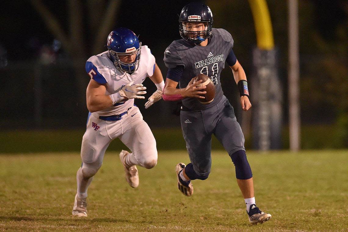 Millbrook quarterback Mason Fortune (11) runs for yardage ahead of Wake Forest’s Max Hines (5) during the first half. The Millbrook Wildcats and the Wake Forest Cougars met in a football game in Raleigh, N.C. on October 29, 2021.