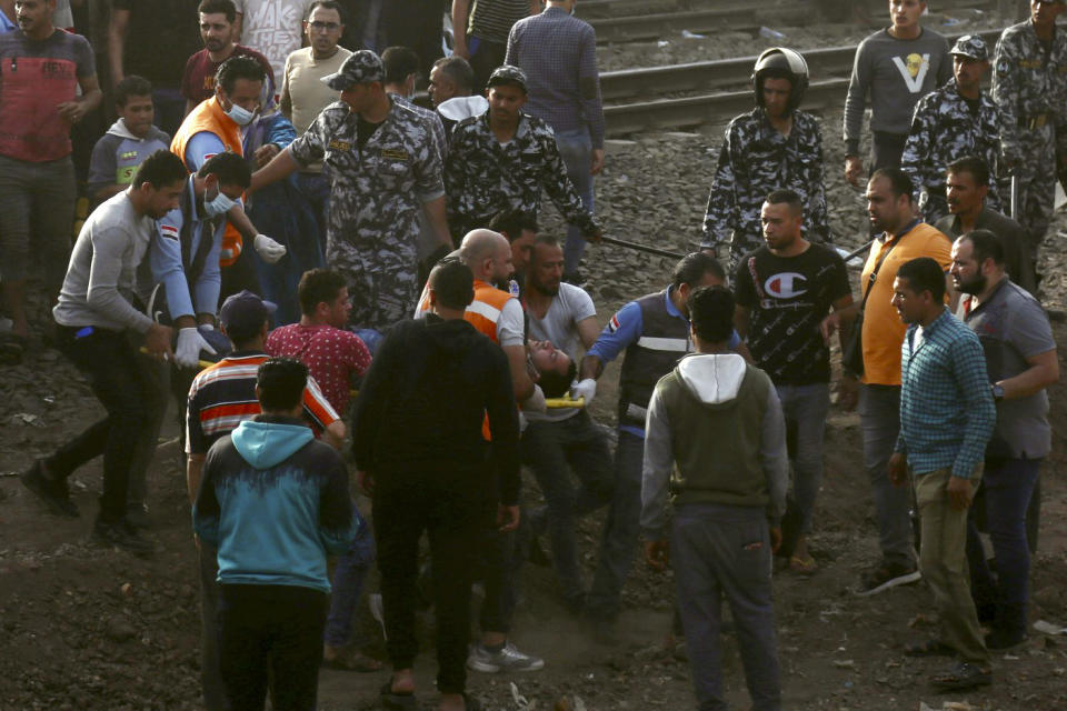 Medics carry an injured man at the site where a passenger train derailed injuring at least 100 people, in Banha, Qalyubia province, Egypt, Sunday, April 18, 2021. At least eight train wagons ran off the railway, the provincial governor's office said in a statement. (AP Photo/Fadel Dawood)