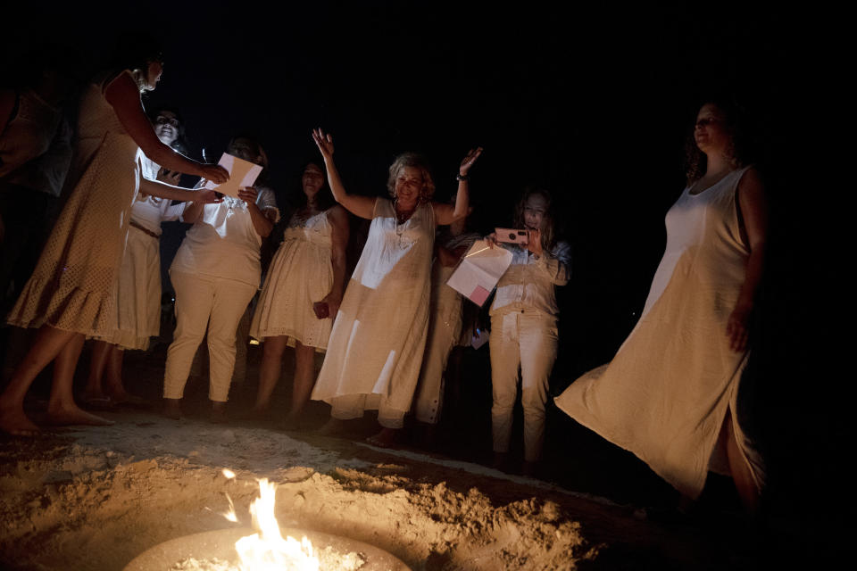 Women take part in a Tashlich ceremony, where they wrote down things they want to release before casting them into a fire, on the beach in Tel Aviv, Israel, Tuesday, Sept. 14, 2021. Tashlich, which means 'to cast away' in Hebrew, is the practice by which Jews go to a large flowing body of water and symbolically 'throw away' their sins by throwing a piece of bread, or similar food, into the water before the Jewish holiday of Yom Kippur, the holiest day in the Jewish year which starts at sundown Wednesday. (AP Photo/Maya Alleruzzo)