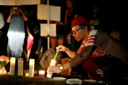 Protesters look at candles at a vigil during a protest over the fatal shooting of an unarmed black man on Tuesday by officers in El Cajon, California, U.S. September 28, 2016. REUTERS/Sandy Huffaker