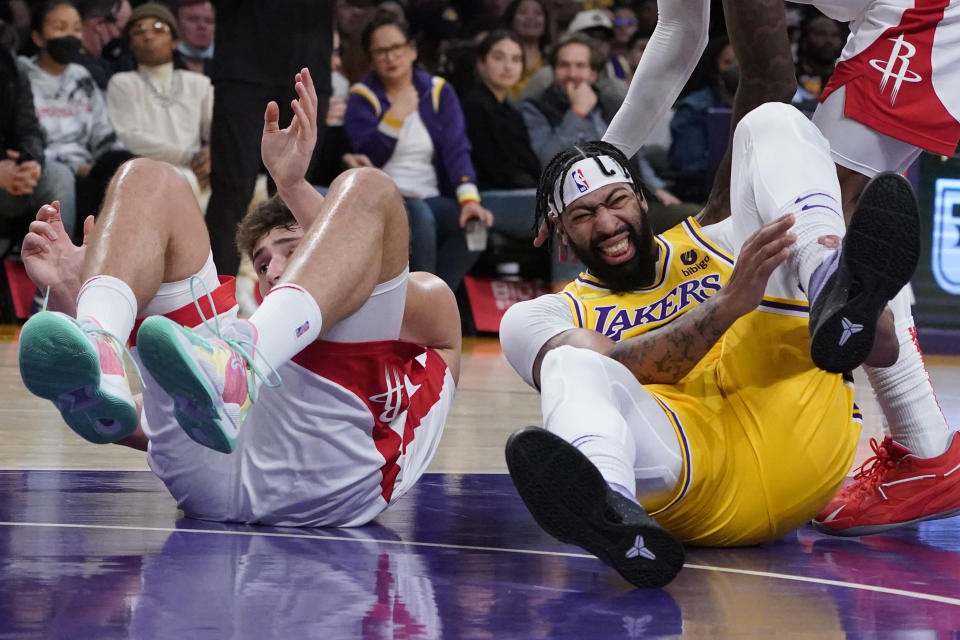 Los Angeles Lakers forward Anthony Davis, right, holds his ankle after falling down during the first half of an NBA basketball game against the Houston Rockets Tuesday, Nov. 2, 2021, in Los Angeles. (AP Photo/Marcio Jose Sanchez)